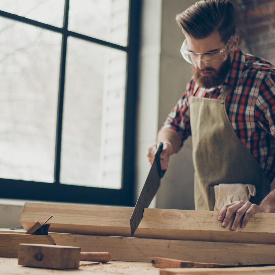young stylish cabinet maker with glasses and hairstyle strong handsome craftsman holding saw and wood blank at workplace 944613244 5af9afc2a18d9e003c17040c scaled 1