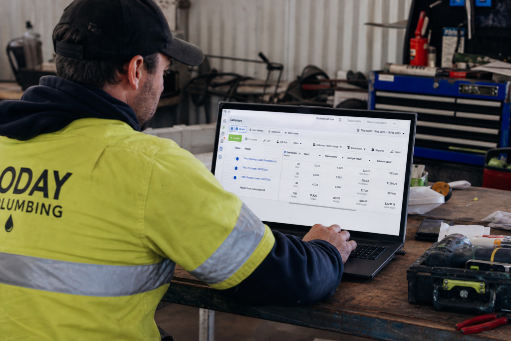 Australian tradie reviewing Facebook Ads campaign performance on laptop in workshop